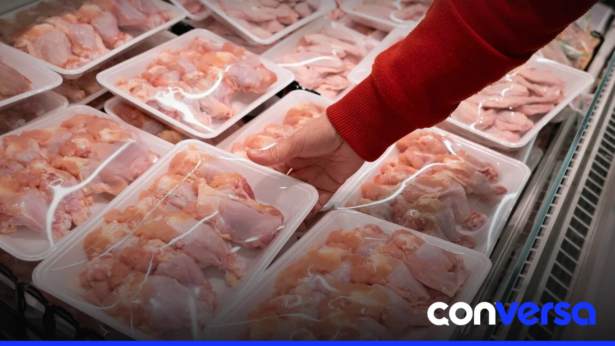 Camareros en un supermercado distribuyen pollo fresco en cajas de venta.